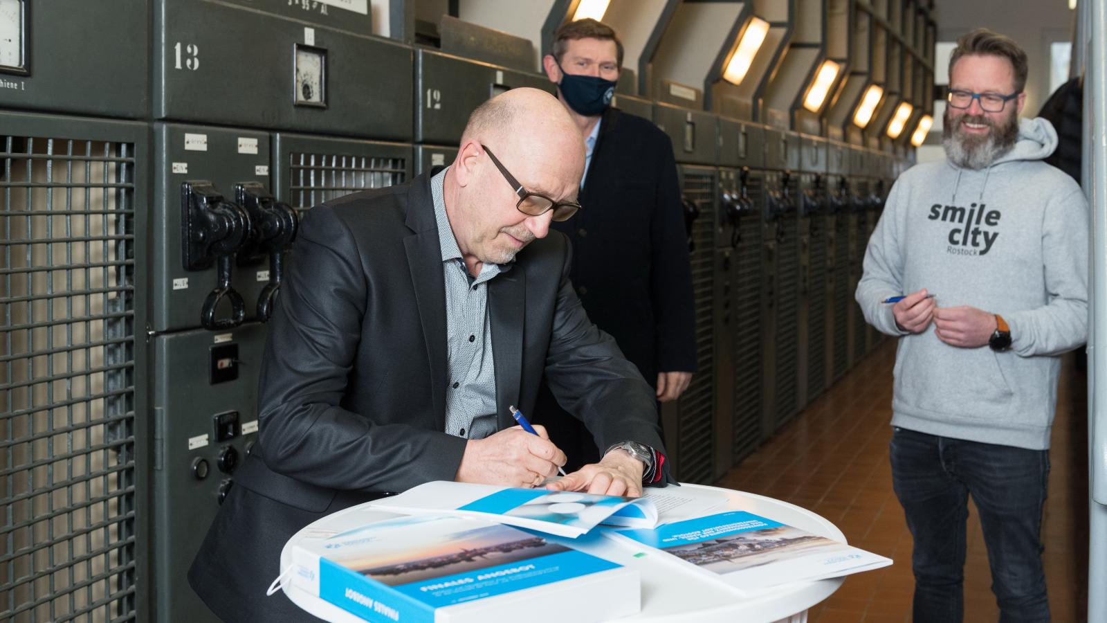 Volker Rattey, Geschäftsführer der Stadtwerke Rostock Netzgesellschaft unterzeichnet den Konzessionsvertrag im Beisein von Oliver Brünnich, Vorstandsvorsitzender der Stadtwerke Rostock AG und Claus Ruhe Madsen, Oberbürgermeister von Rostock. Foto: Margit Wild